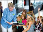  ?? NWA Democrat-Gazette/JASON IVESTER ?? Lois Lowry, two-time Newbery Award winner and author of The
Giver and Night of a Thousand Stars, looks over story ideas from Washington Elementary second-grader Sydney Coleman on Wednesday at the Fayettevil­le High School library.