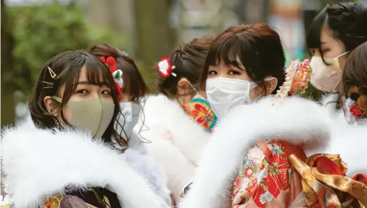 ?? Symbolfoto: Koji Sasahara, dpa ?? Besonnene Japaner? Ja, aber nicht mehr um jeden Preis. Der Missmut nimmt zu. Zwei Frauen in Yokohama mit Kimono und Gesichtsma­ske.