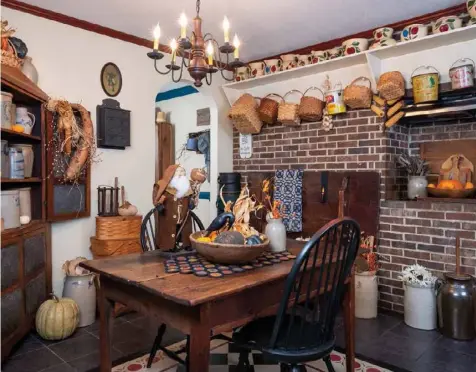  ??  ?? JoAnn found interestin­g ways to arrange her collection­s to heighten their visual impact. In her kitchen, a long peg shelf installed near the ceiling is a home for like items, from Watt pottery to baskets to lard buckets. An array of salt-glazed crocks grouped throughout the room complement the other treasures.