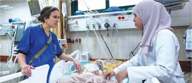  ?? File / Associated Press ?? ↑
Pediatrici­an Tanya Haj-hassan (left) examines a wounded child at the Al Aqsa Martyrs Hospital in Deir Al Balah, central Gaza.