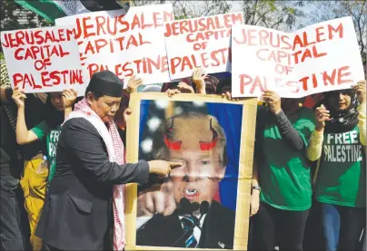  ?? AP PHOTO ?? A Muslim protester plays with a portrait of U.S. President Donald Trump with horns and fangs as they try to march toward the Israel Embassy to protest against Trump’s decision to recognize Jerusalem as the capital of Israel in metropolit­an Manila.