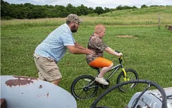  ??  ?? Bryan Latkanich pushes his son, Ryan, on his bike at their home in Deemston, Washington County. Mr. Latkanich says Ryan has many health problems that a toxicology report has linked to well drilling and fracking operations near their house.