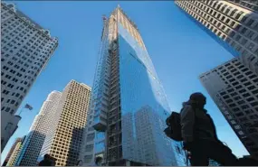  ??  ?? A PEDESTRIAN passes the Wilshire Grand Center going up at Wilshire Boulevard and Figueroa Street. The concrete core rises more than 890 feet above the foundation.