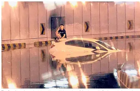  ??  ?? No where to go: A motorist sitting on his car, which was almost fully submerged in flood waters in the tunnel leading from Jalan Tun Razak down to the KLCC carpark.