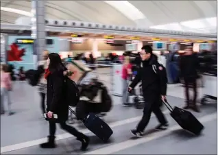  ?? The Canadian Press ?? People carry luggage through Pearson Internatio­nal Airport in Toronto in this file photo. About 700 ground crew at Canada’s busiest airport, who include baggage handlers, cargo handlers, cabin cleaners and other ground staff, have rejected a contract...