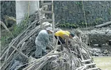  ?? DAVID SANTIAGO/MIAMI HERALD VIA AP ?? Rio Abajo residents, Carlos Ocasio Borrero, left, and Luis Santiago clean up debris in Utuado as recovery efforts from Hurricane Maria continue in Puerto Rico.