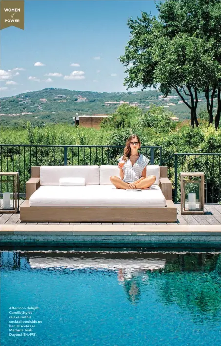  ??  ?? Afternoon delight: Camille Styles relaxes with a cocktail poolside on her RH Outdoor Marbella Teak Daybed ($4,495).