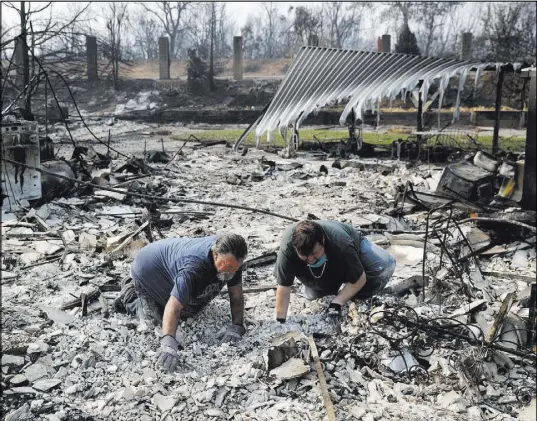  ?? John Locher The Associated Press ?? Rick Kincaid, left, and son Paul Senn sift through remains of their home burned in the Carr Fire on Saturday in Redding, Calif.