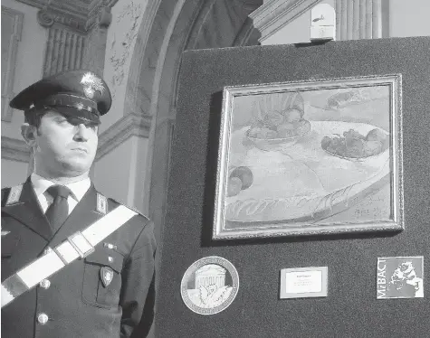  ?? (ANDREAS SOLARO/AFP/Getty Images files ?? A police officer stand next to a painting by French artist Paul Gauguin, one of two art pieces stolen in London in the 1970s. The paintings originally were
owned by Mathilda Marks, daughter of Michael Marks, founder of Marks & Spencer. She died in...