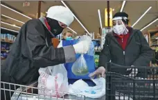  ?? AL BELLO / GETTY IMAGES ?? A shopper and cashier wear protective gear on Tuesday at a grocery store in Merrick, Long Island, New York.