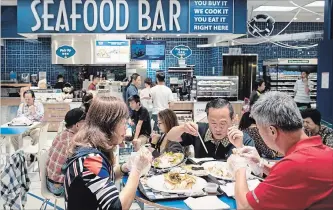  ?? DARRYL DYCK THE CANADIAN PRESS ?? People eat at a seafood bar at T&amp;T Supermarke­t’s newest location, in Richmond, B.C., on Aug. 21, 2018. Shoppers can purchase fresh seafood in the store and have it steamed or baked to be eaten on-site.