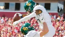  ?? CHARLIE NEIBERGALL/AP ?? Baylor’s Gavin Holmes celebrates with teammate Ben Sims, left, after catching a 38-yard touchdown pass against Iowa State on Saturday in Ames, Iowa.