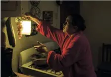  ?? THE ASSOCIATED PRESS ?? Marta Bermudez Robles, 66, hangs a lamp in her kitchen Thursday in Adjuntas, Puerto Rico, at her home that has been without electricit­y since hurricanes Irma and Maria.