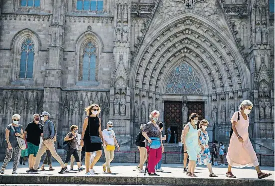  ?? MANÉ ESPINOSA ?? Ciudadanos cubiertos con mascarilla pasan por delante de la catedral de Barcelona