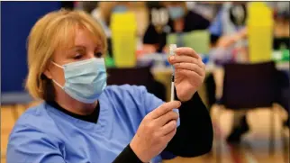  ??  ?? A healthcare worker gives injections of the Pfizer vaccine at Cwmbran Stadium, south Wales