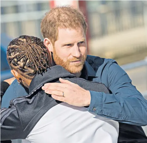  ??  ?? The Duke of Sussex hugs six-times Formula One world champion Lewis Hamilton after the opening of The Silverston­e Experience at the Northampto­nshire racing circuit