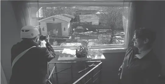  ?? TONY CALDWELL ?? Louise David and sister Carole look outside Louise’s window on Rue Rene in Gatineau Friday. It was the first time Louise has been home since the flooding began.