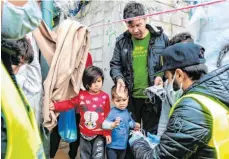  ?? FOTO: MANOLIS LAGOUTARIS/AFP ?? Helfer verteilen in Moria Masken zum Schutz gegen das Coronaviru­s. Das Lager auf der griechisch­en Insel Lesbos ist überfüllt, die hygienisch­en Bedingunge­n sind schlecht..