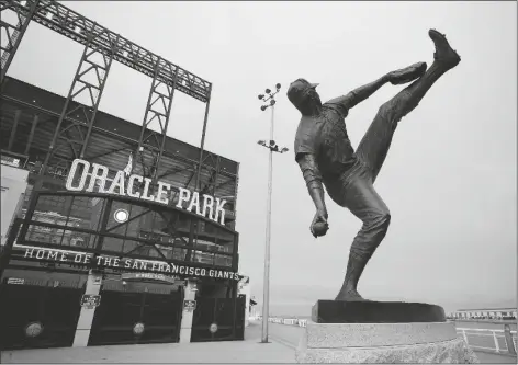 ?? ASSOCIATED PRESS ?? WILDFIRE SMOKE DARKENS THE SKY over a statue of former San Francisco Giants pitcher Juan Marichal outside Oracle Park before a baseball game between the Giants and the Seattle Mariners on Wednesday in San Francisco. People from San Francisco to Seattle woke Wednesday to hazy clouds of smoke lingering in the air, darkening the sky to an eerie orange glow that kept street lights illuminate­d into midday, all thanks to dozens of wildfires throughout the West.