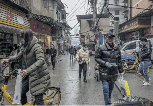  ?? Roman Pilipey / Efe ?? Veïns de Wuhan passegen o fan encàrrecs per un carrer de la ciutat, ahir.