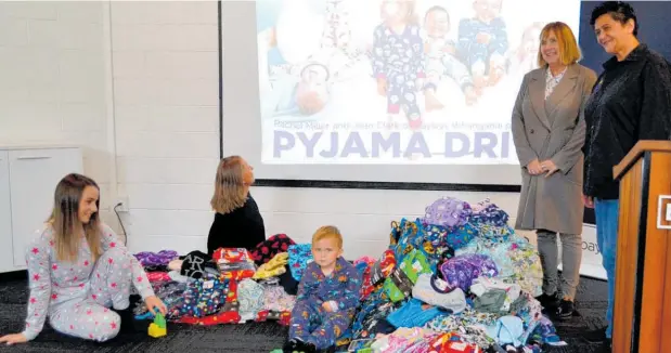  ?? Photo / Paul Brooks ?? Bayleys’ Jean Clark (second from right) with Yvonne Denny from Women’s Refuge and (from left) Emma and Alex (Bayleys admin) and Gordy and a pile of new pyjamas.