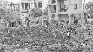  ??  ?? Soldiers and rescuers stand at the site after a big explosion razed five homes and shattered windows of surroundin­g buildings in the northern province of Bac Ninh. — AFP photo