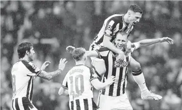  ?? SCOTT HEPPELL AP ?? Newcastle’s Dan Burn (bottom right) celebrates with teammates after scoring his side’s second goal during the Champions League Group F soccer match Wednesday against visiting Paris Saint Germain.