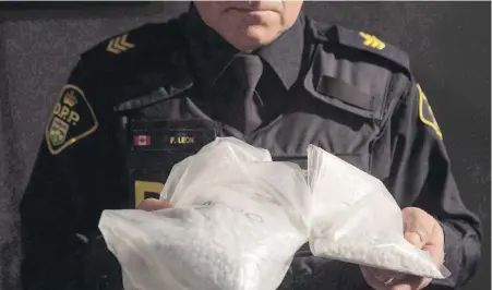  ??  ?? An Ontario Provincial Police officer displays bags containing fentanyl at a news conference in Vaughan, Ont. Police chiefs say illicit use of pill presses has helped increase the supply of street drugs containing synthetic opioids such as fentanyl.