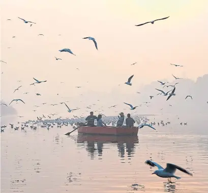  ?? NOEMI CASSANELLI AFP/GETTY IMAGES ?? Indian women take a photograph­er on the Yamuna River on a morning of heavy air pollution in New Delhi.