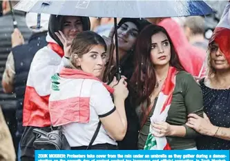  ??  ?? ZOUK MOSBEH: Protesters take cover from the rain under an umbrella as they gather during a demonstrat­ion on the seventh day of protest against tax increases and official corruption, in Zouk Mosbeh, north of the Lebanese capital Beirut. —AFP