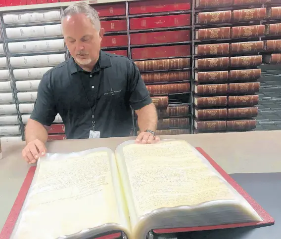  ?? JERRY DAVICH/POST-TRIBUNE PHOTOS ?? Porter County Recorder Chuck Harris looks through one of his office’s oldest documents, the first land deed from 1836, signed by the county recorder at the time, Cyrus Spurlock, a local minister. His official seal was the word“seal”with a drawn cloud circled around it.