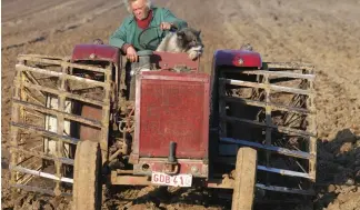  ?? ?? A farmer and his dog sit on a tractor and ploughs the land, in Passendale, western Belgium.