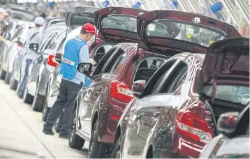  ??  ?? Men work at a Mitsubishi auto plant in Chon Buri. The OIE says a prolonged trade war will hurt every country.