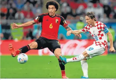  ?? TOLGA BOZOGLU / EFE ?? Modric dispara con su pierna izquierda acosado por Axel Witsel.