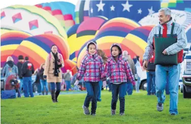  ?? MARLA BROSE/JOURNAL ?? Twins Kira, left, and Miya Knudsen, walk among the inflating balloons with their father, Allan Knudsen, of Denver.