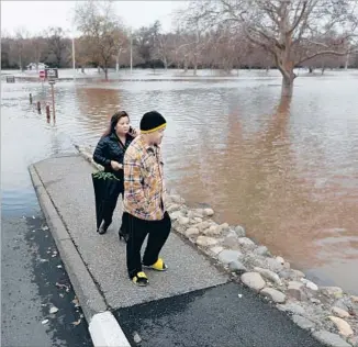  ?? Gary Coronado Los Angeles Times ?? A STORM-SWOLLEN American River this week f loods Sacramento’s Discovery Park as Christy Moua and Chou Thao take a look. The storm system made a significan­t dent in the state’s drought.