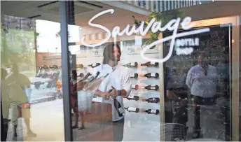  ??  ?? Patrons peer through the windows at wine bottles and staff inside Sauvage Bottle Shop at the Churchill in downtown Phoenix.