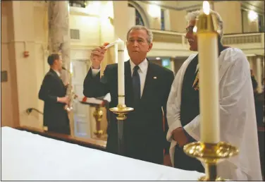  ?? (File Photo/White House/Eric Draper) ?? President George W. Bush lights a candle Sept. 11, 2007, accompanie­d by the Rev. Luis Leon, during a service of prayer and remembranc­e at St. John’s Episcopal Church in Washington marking the sixth anniversar­y of the Sept. 11 terrorist attacks. “If he was in town, he was in church,” Leon said of Bush.