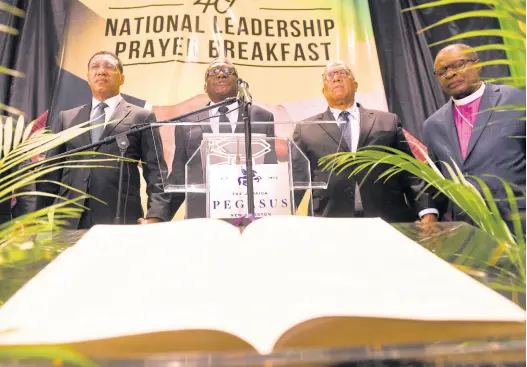  ?? MAKYN/CHIEF PHOTO EDITOR RICARDO ?? Prime Minister Andrew Holness (left) and Bishop Conrad Pitkin (second left), custos rotulorum of St James and pastor of the Faith Temple Assemblies of God in Montego Bay, pray with Opposition Leader Dr Peter Phillips (second right) and Reverend Stanley Clarke, chairman of the National Leadership Prayer Breakfast Committee, during the National Leadership Prayer Breakfast held yesterday at The Jamaica Pegasus hotel in New Kingston.