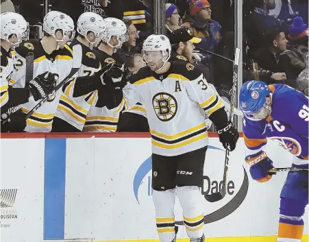  ?? AP PHOTO ?? TEAMWORK: Patrice Bergeron celebrates his goal with the bench as he skates past dejected Islanders captain John Tavares during the Bruins’ 5-1 victory last night in New York.