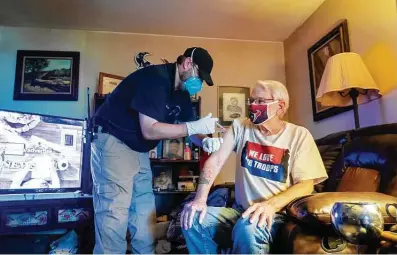  ?? Photos by Mark Mulligan / Staff photograph­er ?? Chambers County paramedic Danny Burke gives a second dose of the Moderna vaccine to David Phelps in Phelps’ home.