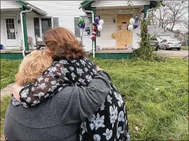  ?? ?? Debby Seymour and Teresa Petersen, loved ones of Gloria Dickinson, embrace in front of the house where Dickinson was found during a vigil on North Douglas Avenue on Monday evening.