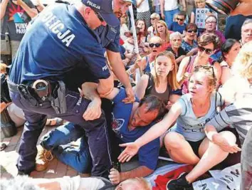  ??  ?? Above: Police officers detain people during a protest next to the Law and Justice party headquarte­rs in Warsaw, Poland, yesterday.