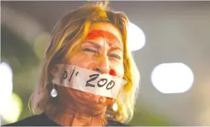  ?? (Hannah McKay/Reuters) ?? A WOMAN WITH her mouth sealed reacts during a protest marking 200 days since the start of the Gaza war, in Tel Aviv on Tuesday.