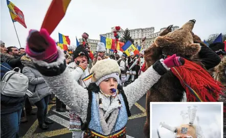  ?? ?? Making a stand: A child wearing a traditiona­l Romanian dress as others wear bear skins singing anti-restrictio­n Christmas carols during a protest in Bucharest, Romania while another protester (inset) wears a mask riddled with syringes. — AFP