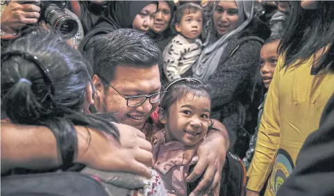  ?? AFP ?? A family member hugs daughters of Mohamad Nor Azrin Md Zin, Annur Zhafirah, five, right, and Annur Zulaikha, six, left upon arriving at the Bunga Raya complex at Kuala Lumpur.