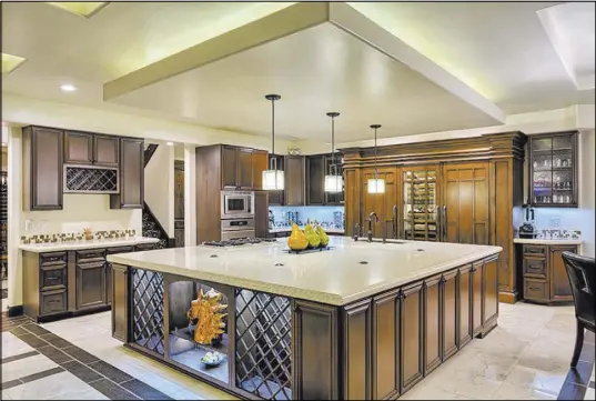  ?? PHOTOS COURTESY OF LUXURY ESTATES INTERNATIO­NAL ?? The kitchen features a 20-foot-by-20-foot center island with Italian Caesarston­e Dreamy Marfil countertop, customized alder wood cabinetry and updated stainless-steel Dacor appliances. At right, the new gas fireplace creates a warm and inviting...