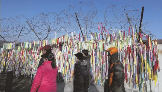  ?? AP PHOTO ?? IMAGE ENHANCEMEN­T: Visitors walk by the wire fence decorated with ribbons carrying messages to wish for the reunificat­ion of the two Koreas at the Imjingak Pavilion in Paju, South Korea yesterday.