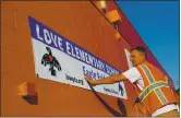  ?? STAFF FILE PHOTO ?? Constructi­on worker Matt Martin attaches a banner on Alameda’s Love Elementary School, formerly named Haight Elementary.