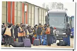  ??  ?? Workers help migrants toting their luggage to board buses and leave a camp being demolished in Calais, France. Thousands had crowded the site in the futile hope of crossing to Britain.